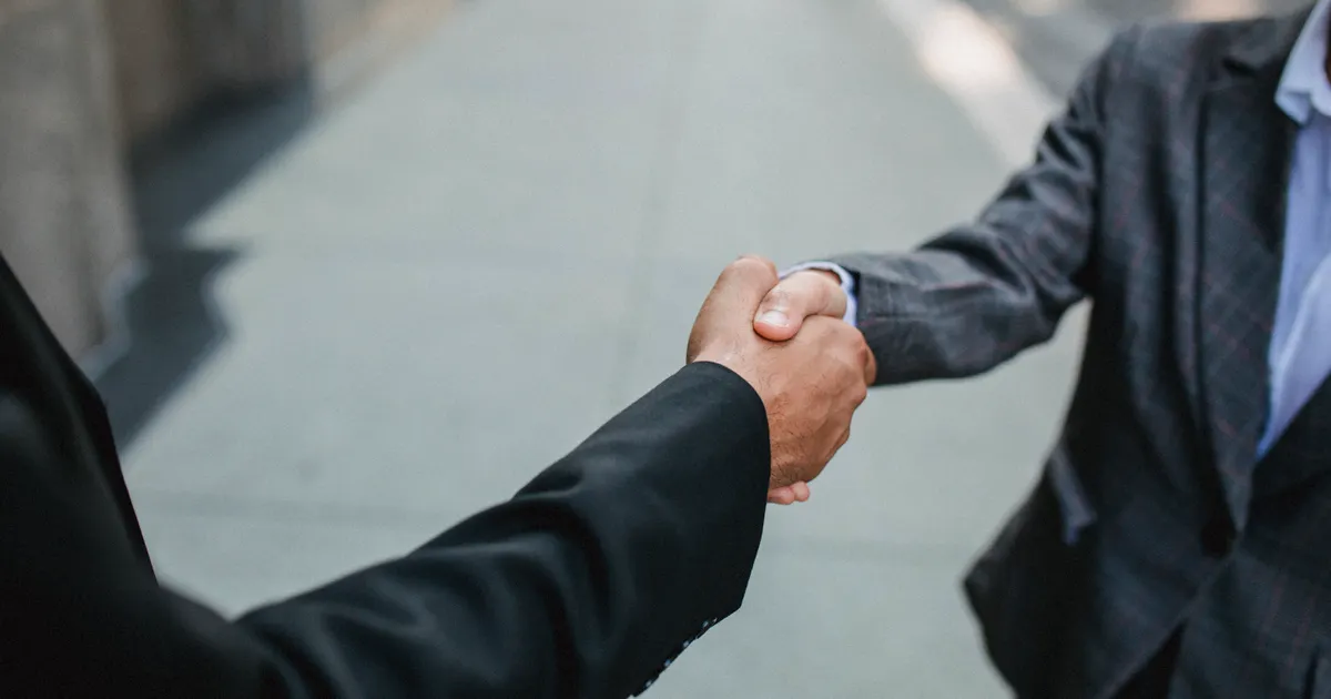 Close-up of two businessmen shaking hands outside, symbolizing partnership and…, illustrating the section “Renewal, notice periods and the exit ramp”